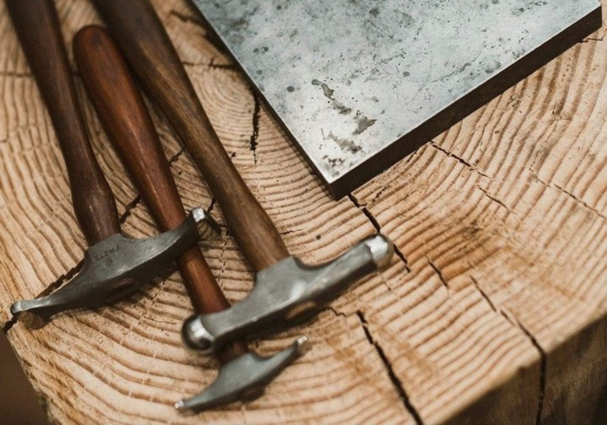 Two hammers on a wooden surface with a metal block - Nina Alexandra